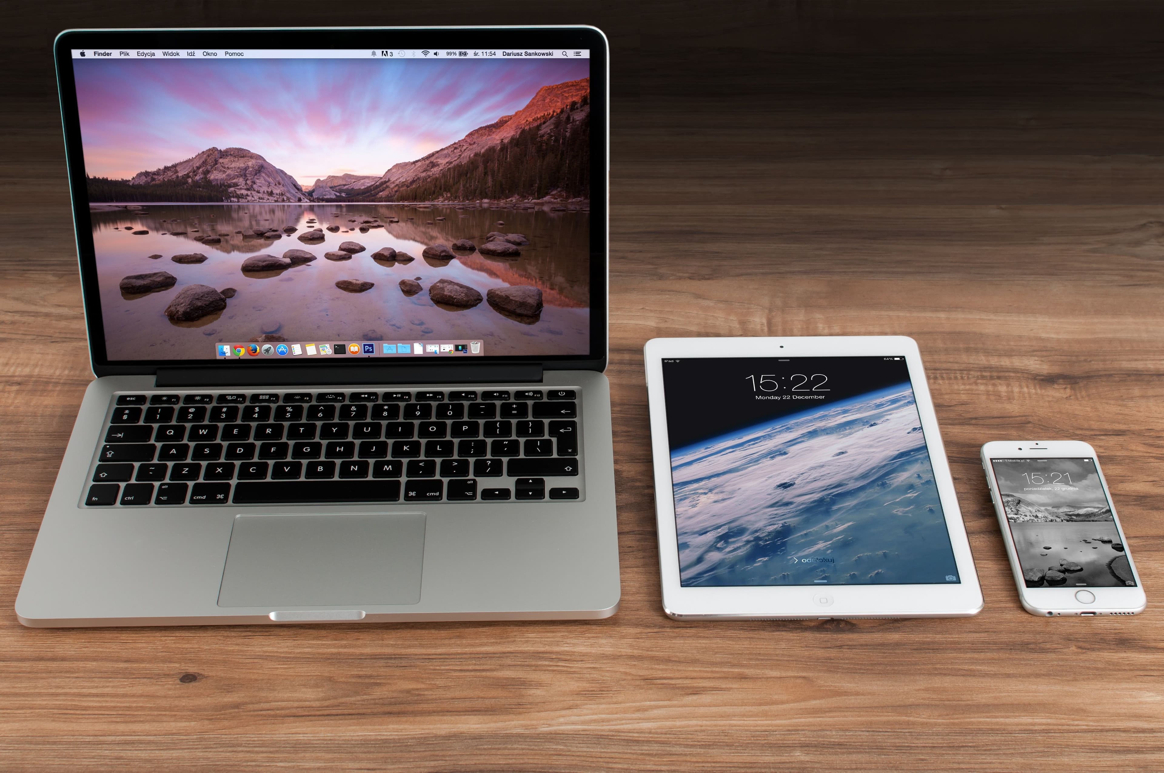 جهاز MacBook وiPad وiPhone جنبًا إلى جنب على مكتب خشبي